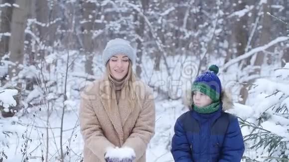 冬天的乐趣母亲和儿子在冬天的森林或公园里向空中撒雪快乐视频的预览图