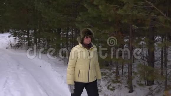 在冬天散步时老妇人摸着树枝嗅着树枝视频的预览图
