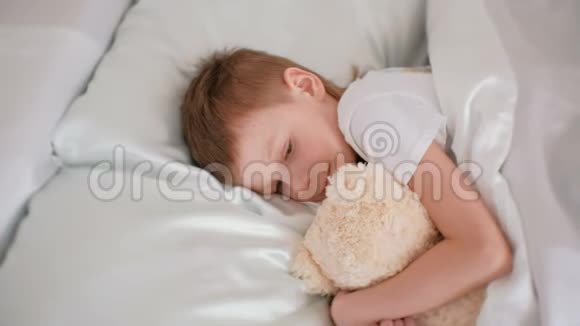 七岁的男孩抱着玩具熊睡着了视频的预览图
