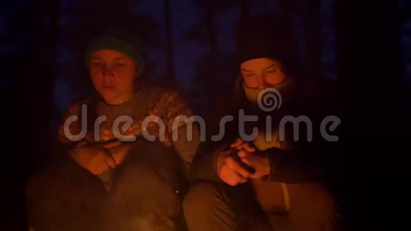 晚上疲惫的少女们坐在树林里的篝火旁打哈欠视频的预览图