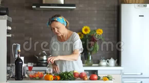 成熟的素食者在厨房里准备一份沙拉用植物油填充健康饮食素食主义视频的预览图