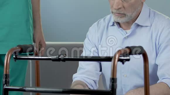 老人坐在步行架前护士把手放在他的肩膀上视频的预览图