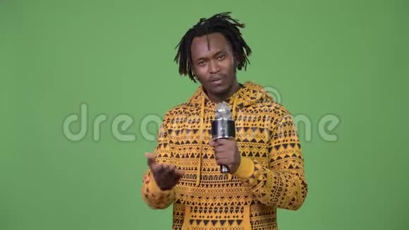 年轻英俊的非洲男人在麦克风上讲话展示一些东西视频的预览图