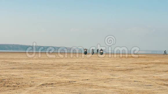 三个骑摩托车的人骑在沙滩附近的沙漠从很远免费乘车视频的预览图