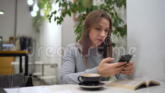 美丽的女人花时间在咖啡馆里使用智能手机和喝咖啡视频的预览图