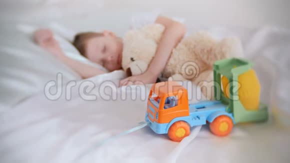 七岁的男孩和他的玩具熊和塑料汽车睡觉专注于玩具车视频的预览图