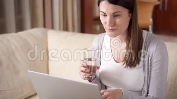 微笑的职业妇女在家里工作在笔记本电脑上喝水家庭办公概念视频的预览图