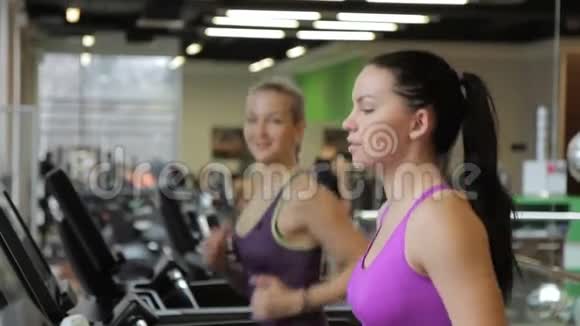 两个女朋友正在现代健身房里踩着跑步机和AECH交谈视频的预览图