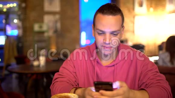 西班牙裔年轻人使用移动电话在舒适的咖啡店西班牙裔迷人的微笑肖像视频的预览图