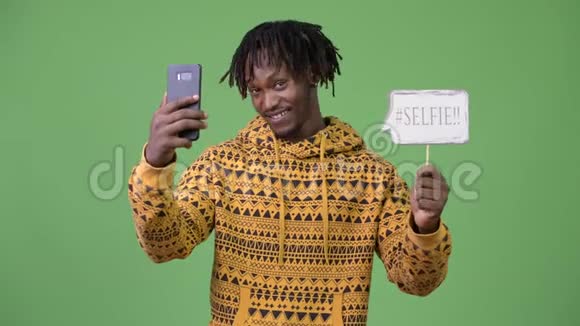 年轻英俊的非洲男人拿着电话和自拍纸标志视频的预览图