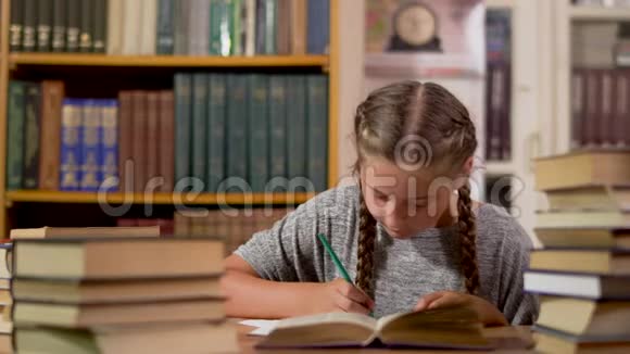 小女孩在图书馆的一张桌子上写字视频的预览图