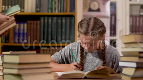 小女孩在图书馆的一张桌子上写字视频的预览图