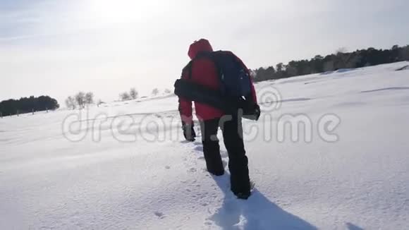 人雪冬的脚印概念之旅克服困难日落时分的冬夜平原上的徒步旅行者视频的预览图