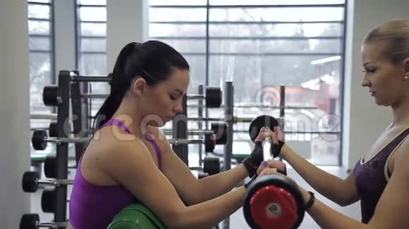 女教练正在教女运动员如何在现代健身房做巴贝尔训练视频的预览图