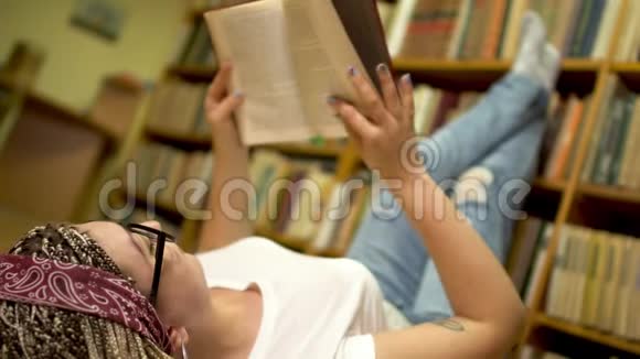 漂亮的女孩正在图书馆的地板上读一本书视频的预览图