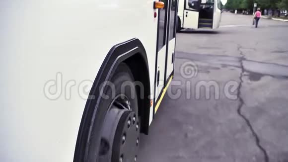 在灰色沥青背景下白色巴士和巴士轮停车的侧面视图场景关闭白色客车视频的预览图