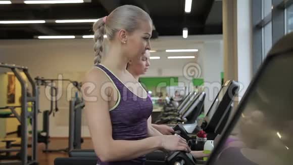 这两位女性朋友正在现代健身房的跑步机上完成有氧训练视频的预览图