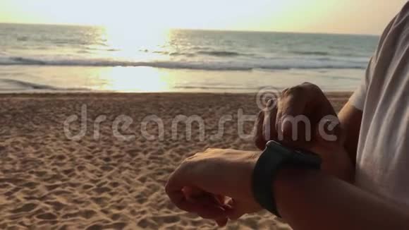 活跃的生活方式男人游客看科技智能手表特写宏观特写手臂海滩触摸屏手腕上视频的预览图