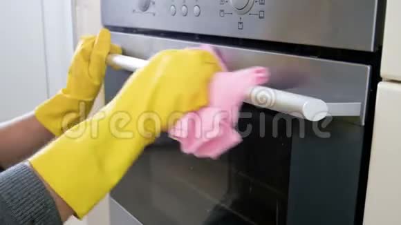 特写4k镜头年轻女子戴着黄色橡胶手套清洗电烤箱手柄视频的预览图