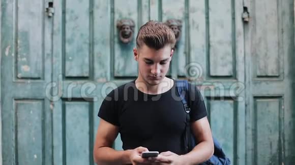 在旧城使用手机的英俊年轻人的肖像慢动作视频的预览图