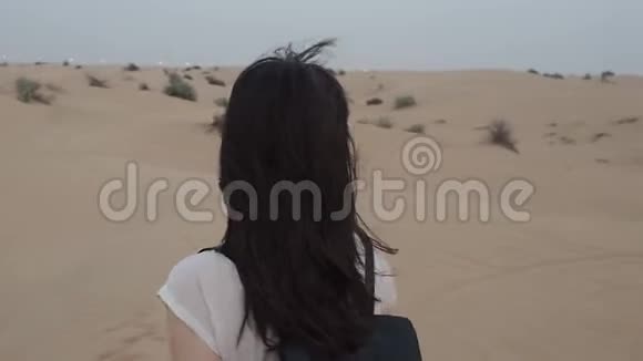 沙漠中的年轻女游客带背包的女孩在沙漠里散步视频的预览图