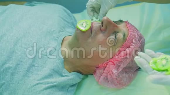 化妆师的女人的手在男人的脸上戴上了猕猴桃的面具视频的预览图
