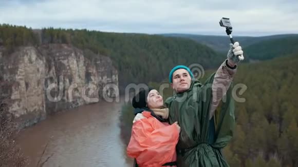 年轻夫妇在山河背景的山坡上自拍视频的预览图