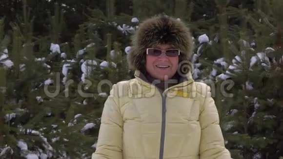 在冬天的森林里散步时一位快乐的老年妇女正望着镜头视频的预览图