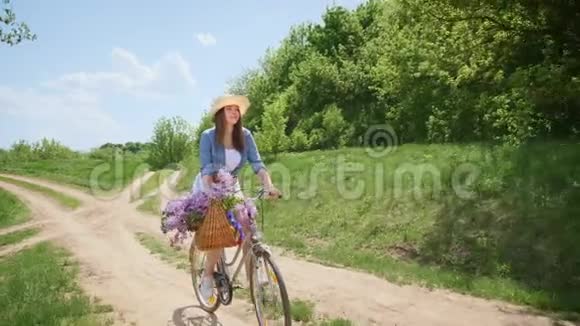 戴着帽子的漂亮女孩骑着自行车在大自然中旅行视频的预览图