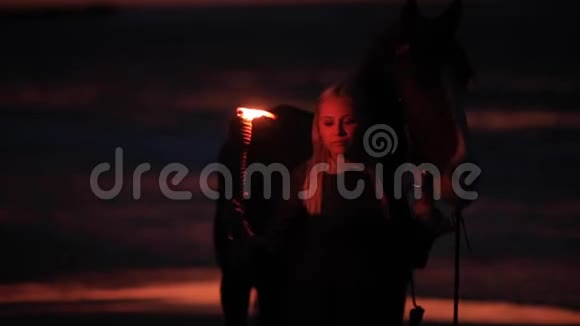 夜晚带着火的女孩带着马走在海滨视频的预览图