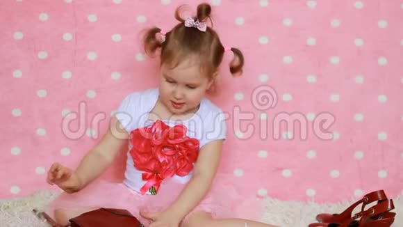 时尚界人士一个小女孩带着一个红色的袋子眼镜阳光和鞋子有趣的孩子粉色背景魅力视频的预览图