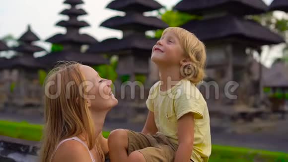 一名年轻女子和她的儿子在巴厘岛的塔曼阿云寺周围行走时被慢镜头拍到视频的预览图