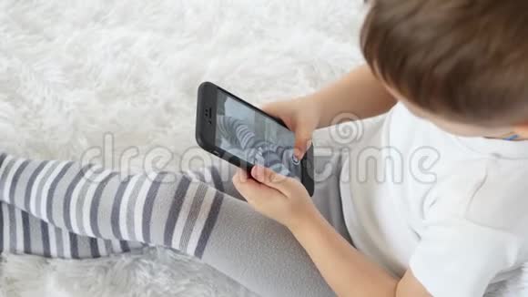 一个孩子喜欢在白色背景下玩手机拍他的腿特写视频的预览图