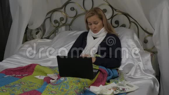 一个生病的女人在笔记本电脑上和医生聊天的视频女孩躺在床上脖子上戴着一条温暖的围巾慢动作视频的预览图