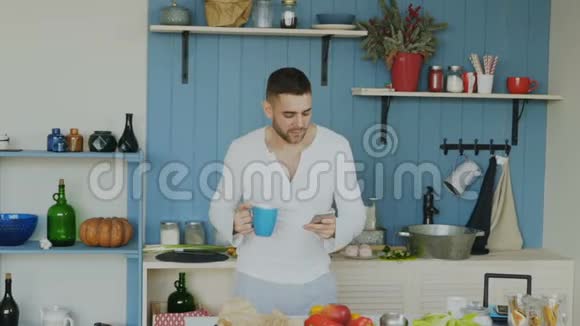在智能手机上浏览社交媒体时帅哥在厨房里跳舞唱歌视频的预览图