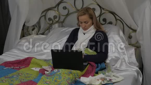 一个生病的女人在笔记本电脑上和医生聊天的视频女孩躺在床上脖子上戴着一条温暖的围巾慢动作视频的预览图