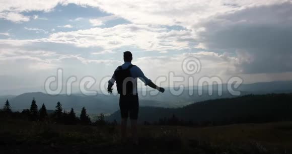 孤独地走在山里一个背着背包的人站在美丽的山景前在蓝色下伸展视频的预览图