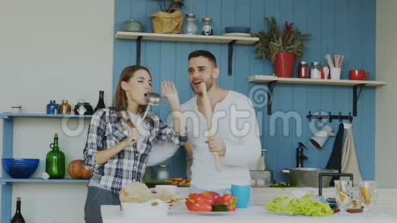 年轻快乐的一对夫妇在家里的厨房里摆桌子吃早餐时尽情地跳舞唱歌视频的预览图