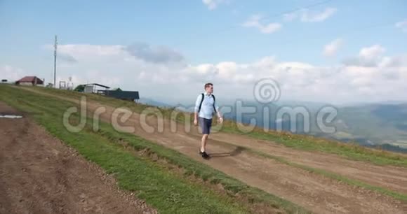 孤独地走在山里英俊的年轻人肩上背着一个背包沿着山走环顾四周视频的预览图