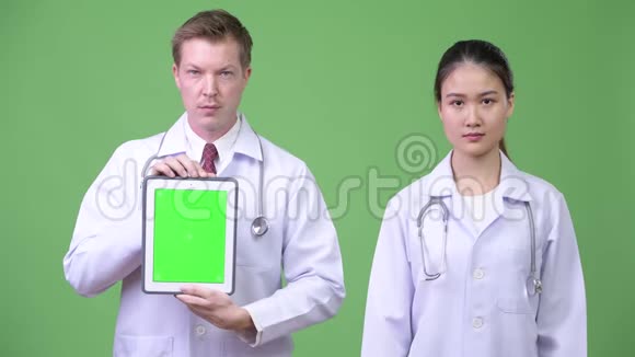 多民族夫妻医生一起展示数字平板电脑视频的预览图