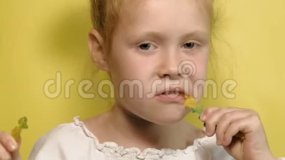 黄色背景上带彩色果冻的快乐小女孩特写肖像视频的预览图