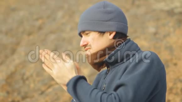 一个人试图在寒冷中温暖他的手在他的手上呼吸并摩擦视频的预览图
