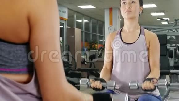 培训一个年轻的女人用哑铃抽她的手肌肉从镜子里看视频的预览图