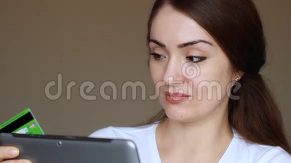 年轻妇女使用平板电脑进行网上银行在网上商店购物并通过信用卡购买视频的预览图