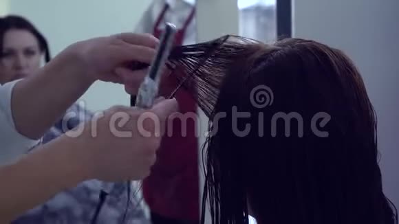 美容院理发店发型师给理发女孩做热剪发型师进行大师班特写镜头视频的预览图