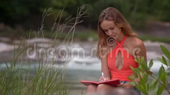 风吹发女郎在河边的笔记本上写视频的预览图