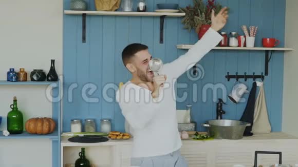 在家厨房做饭的时候一个英俊的年轻滑稽男子用勺子跳舞唱歌视频的预览图