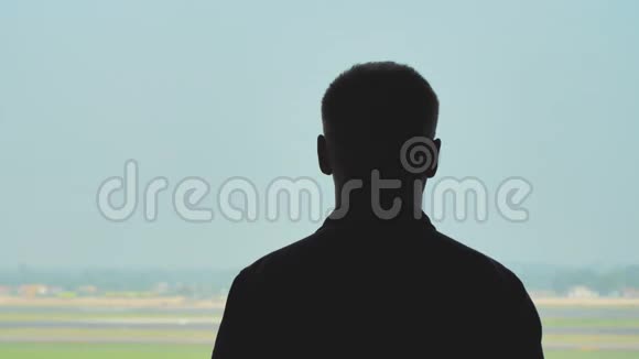 一个年轻人看着飞机在蓝天上起飞的剪影视频的预览图