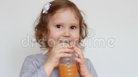 小可爱的女孩从瓶子里喝橘子饮料婴儿和新鲜果汁冰沙柠檬水新鲜视频的预览图