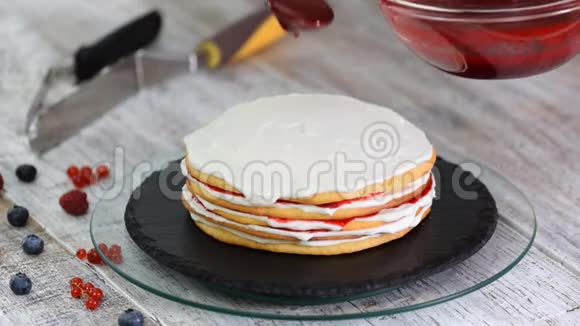 女性糕点厨师用旋转蛋糕制作美味的海绵蛋糕鲜奶油和浆果果酱视频的预览图